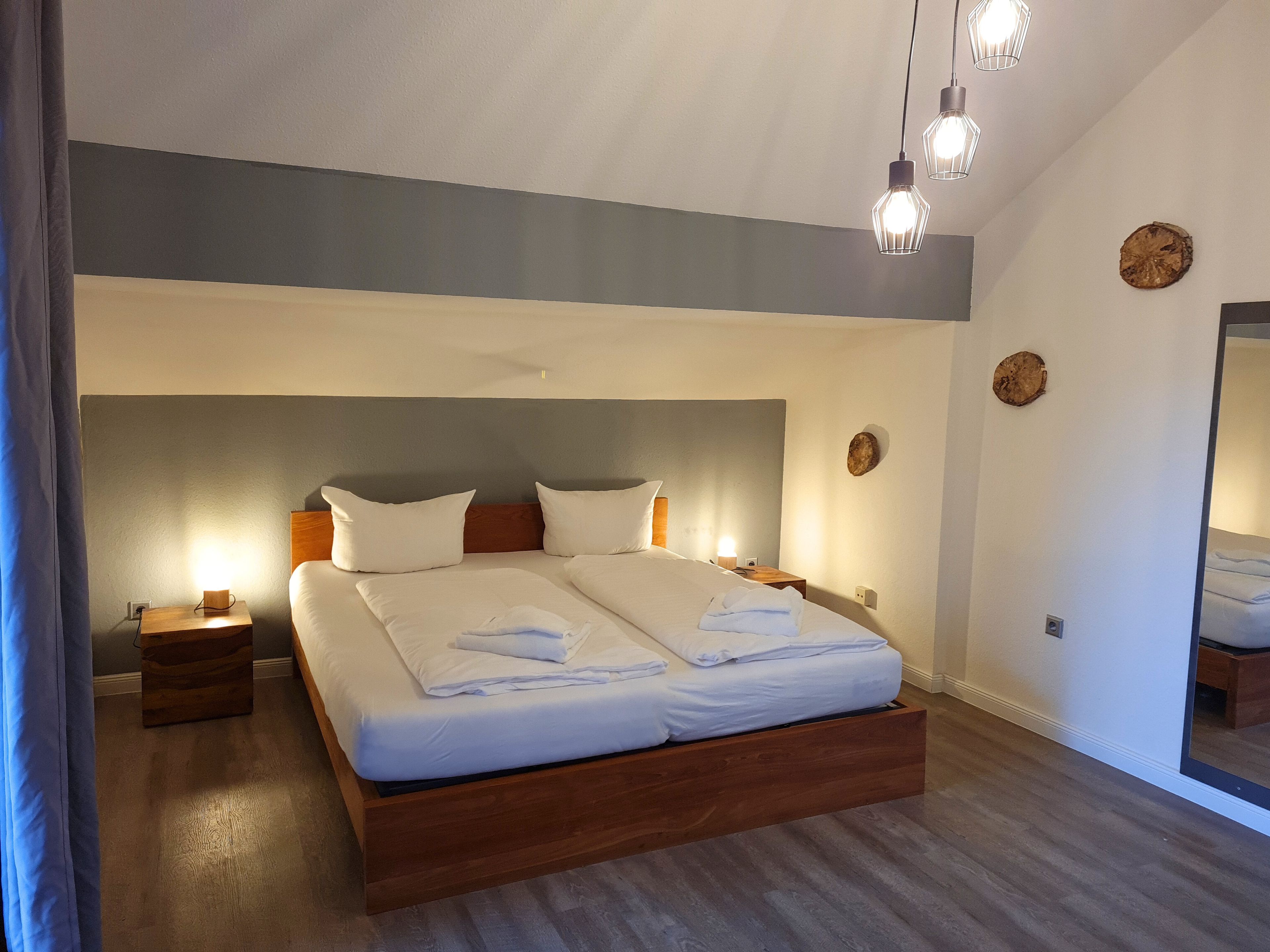 Un dormitorio moderno con una cama grande, mesitas de noche y un espejo.