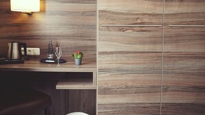 Een moderne keuken met houten kastjes, een waterkoker, een wijnglas en een kleine potplant.