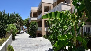 Un hotel de varios pisos con un patio central, rodeado de abundante vegetación y un cielo azul despejado.