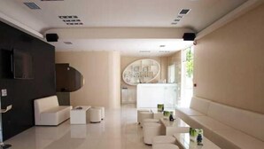 Un interior moderno con una zona de estar, una cocina al fondo y un ventanal que proporciona luz natural.