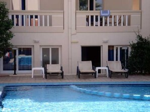 A poolside area with lounge chairs and a building with balconies. - Akatos Hotel (Chania)