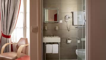 Un baño con lavamanos, espejo, toallero y retrete.