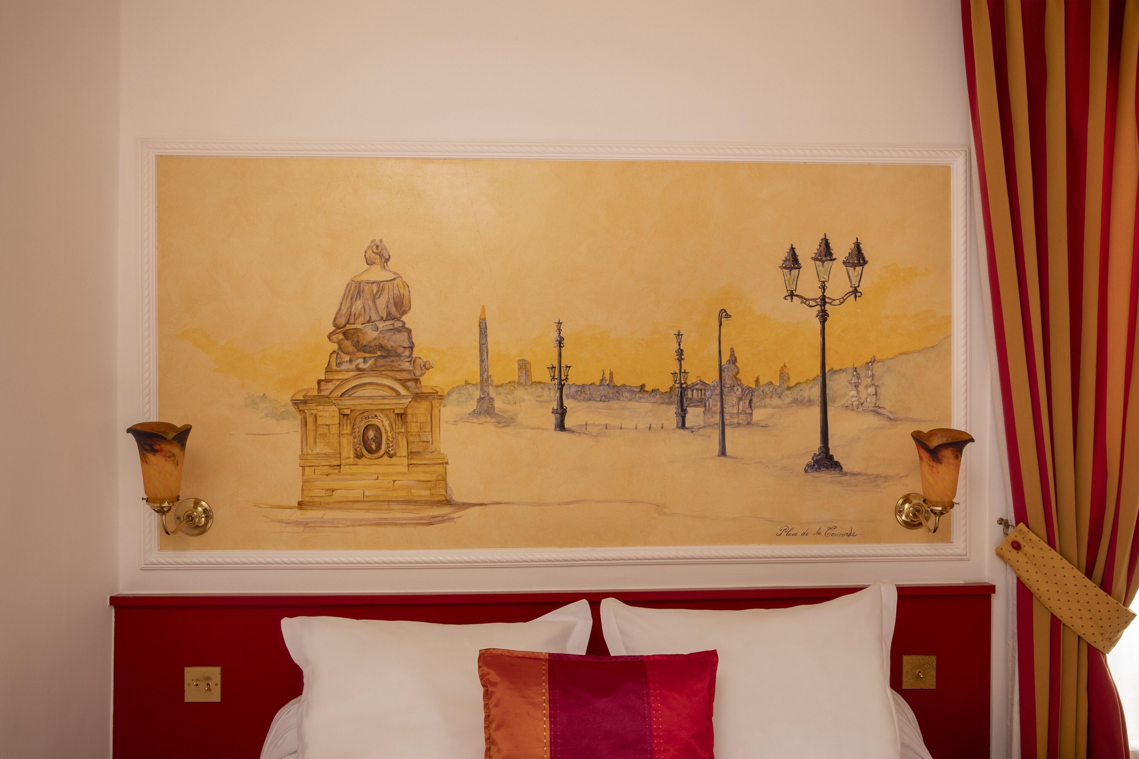 A hotel room with a large painting of a historical scene on the wall, a red headboard, and two wall sconces.