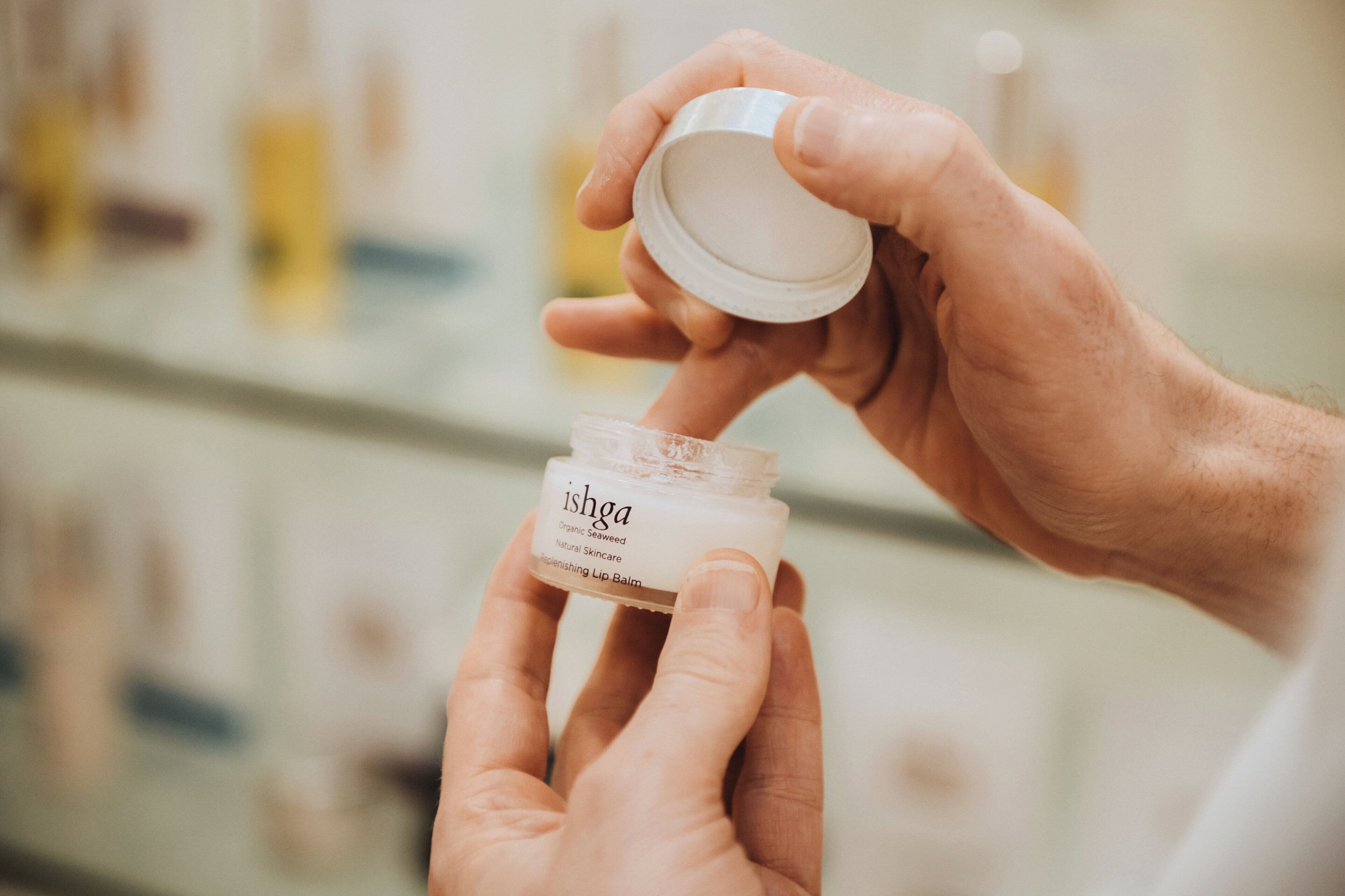 A person holding a jar of Ishga Organic Seaweed Natural Skincare Replenishing Lip Balm.
