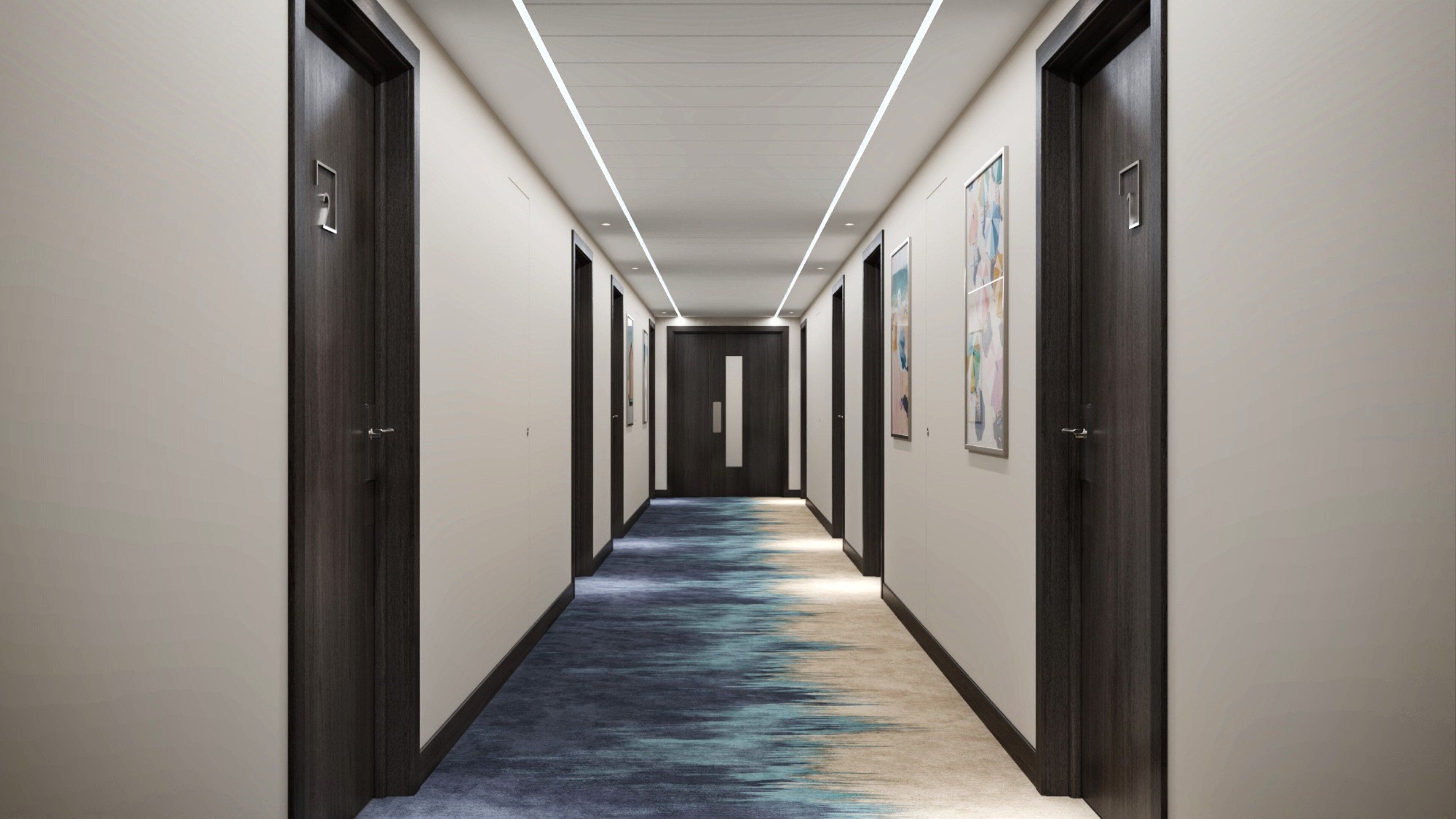 A hallway with dark wooden doors, white walls, and a carpet with a blue and black pattern.