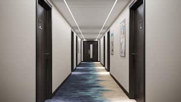 Un couloir avec des portes en bois foncé, des murs blancs et un tapis aux motifs bleus et noirs.