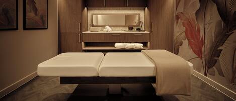 Una sala de spa amb un llit de massatge, armaris de fusta, un mirall i una paret amb un disseny de fulles.