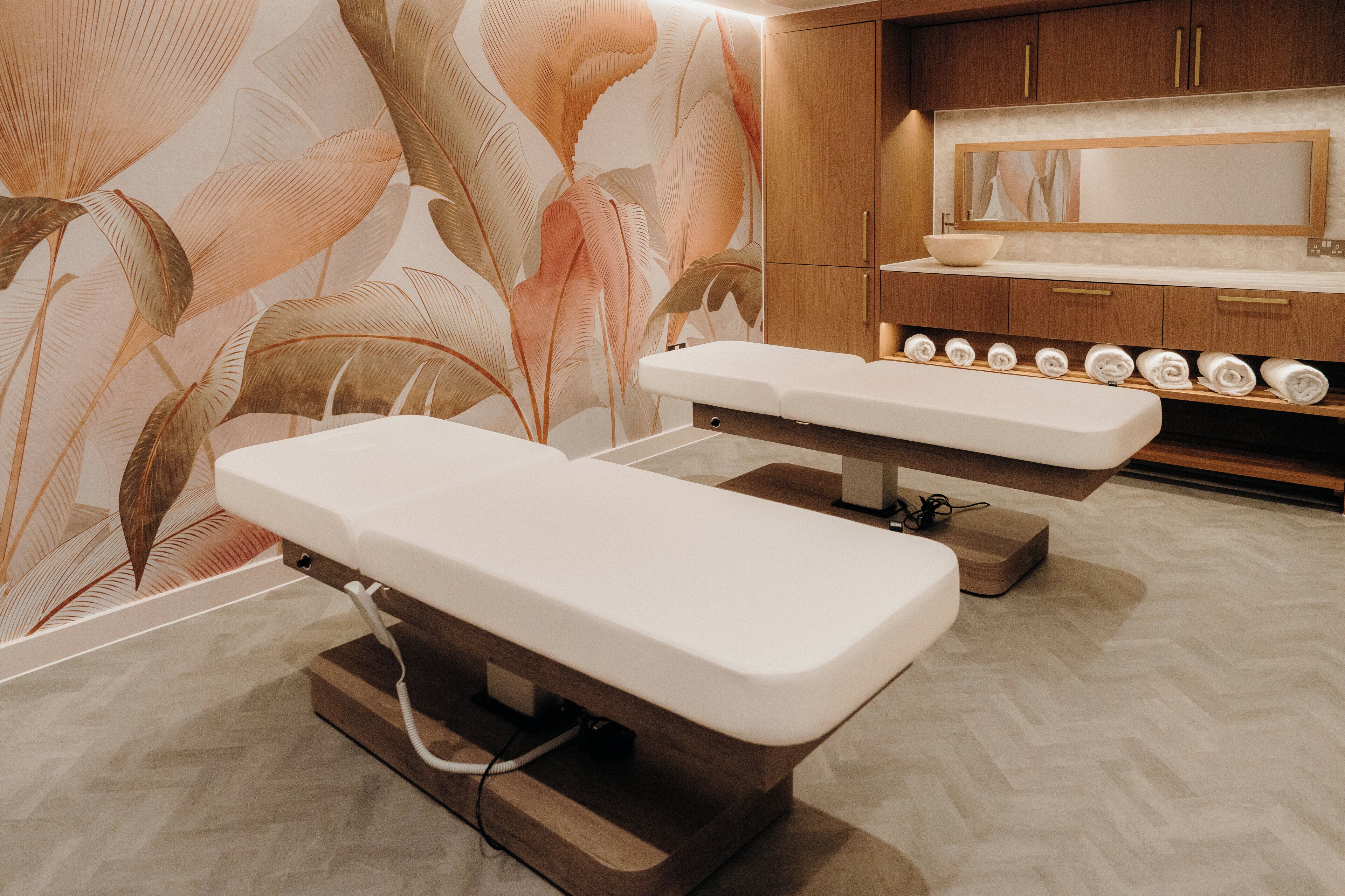 A treatment room with a wooden cabinet, a large mirror, and a row of towels.