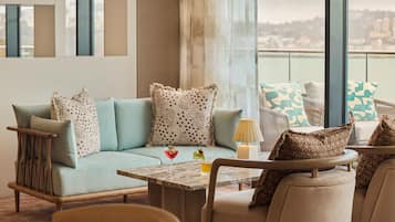 Un área de descanso moderna con sofá, sillones, una mesa y vistas a la ciudad.
