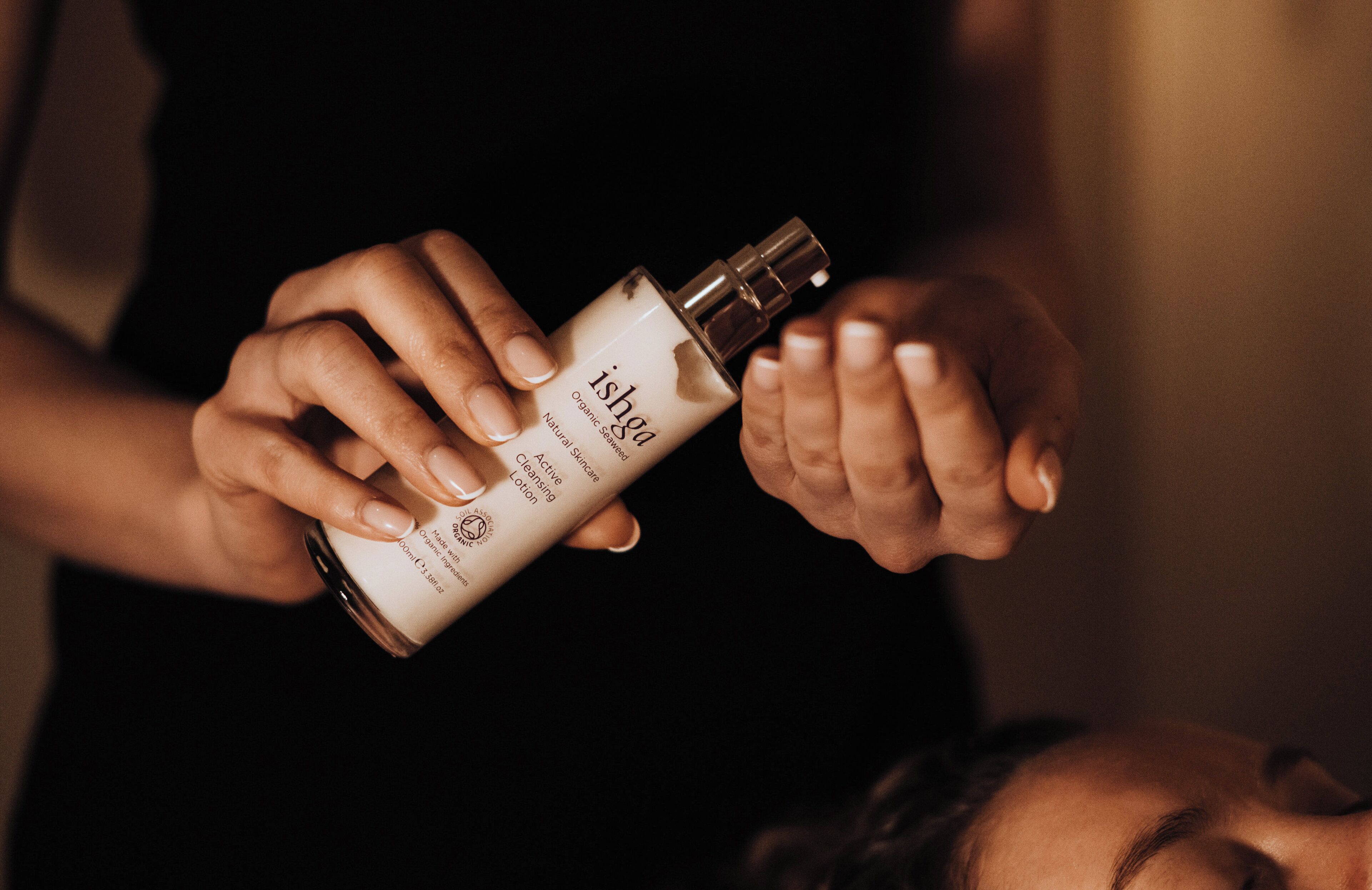 A person holding a bottle of organic skincare product.