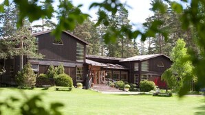 A large, rustic building with a prominent entrance, surrounded by a well-maintained lawn and trees. - Mullsjö Hotell och konferens (Mullsjö)