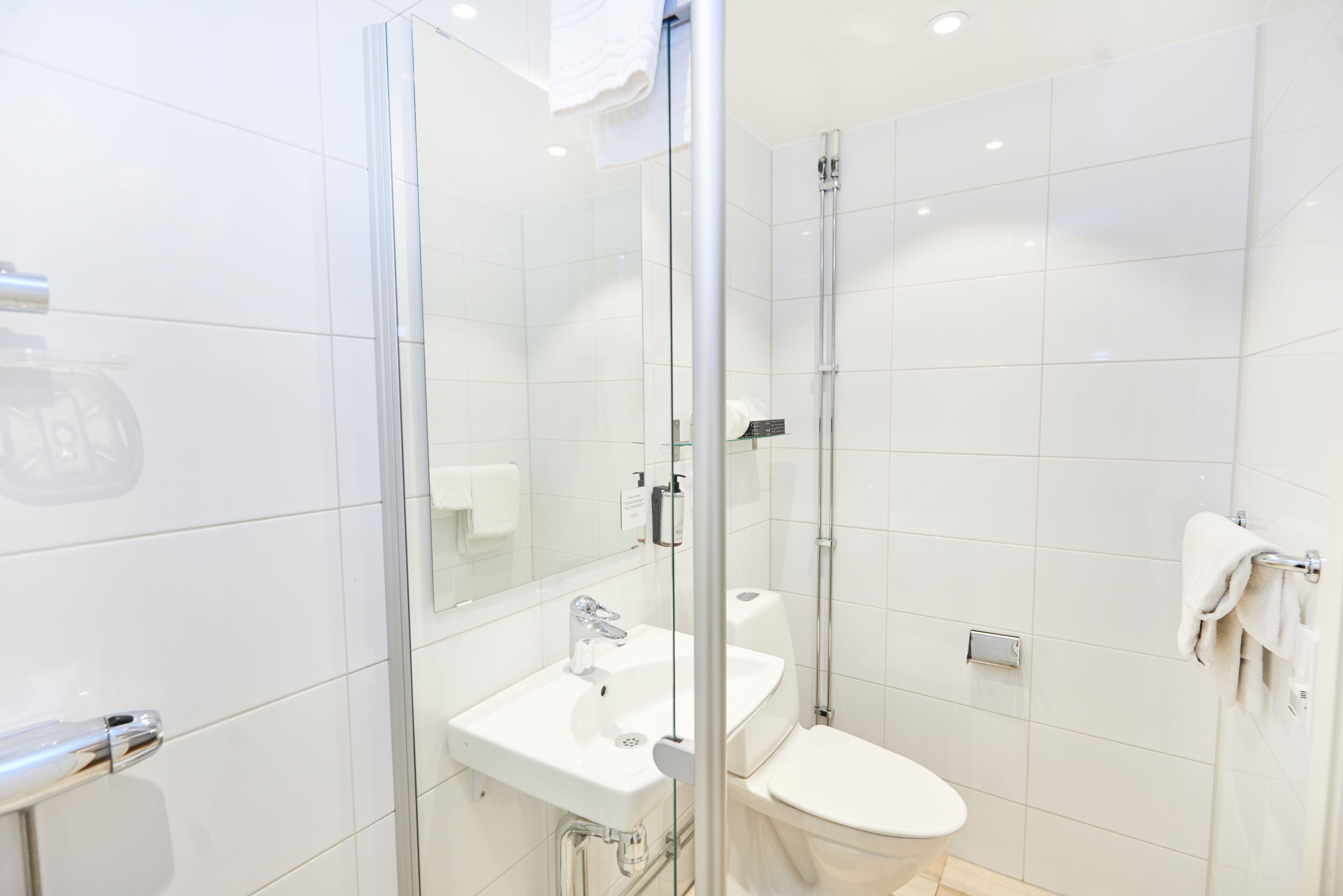 Ein modernes Badezimmer mit Duschkabine aus Glas, einem weißen Waschbecken und einer Toilette.