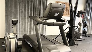 A gym with a treadmill, stationary bike, and rowing machine.