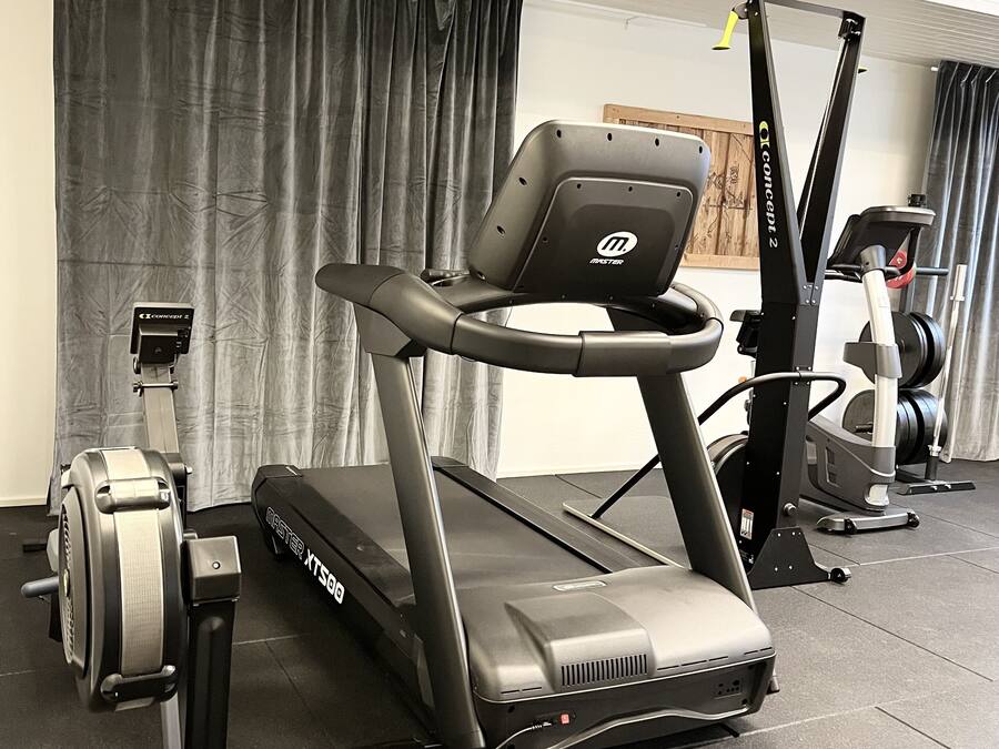 A gym with a treadmill, stationary bike, and rowing machine.