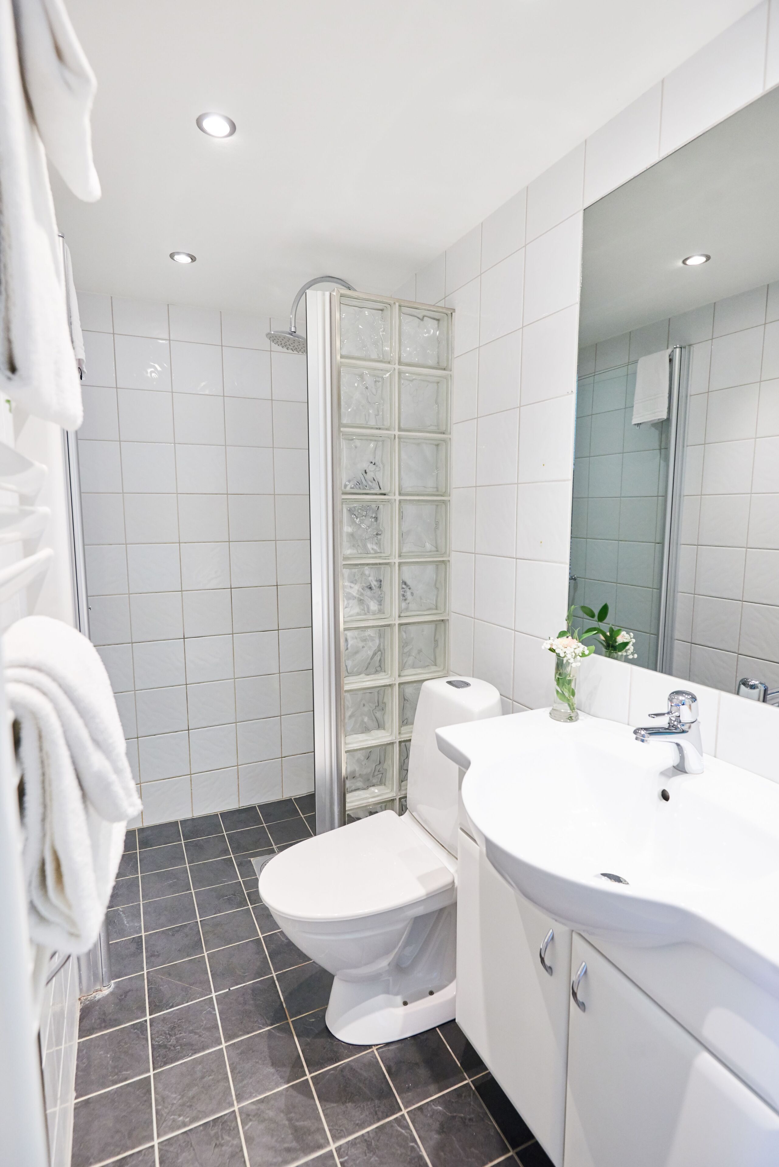 A modern bathroom with a white sink, toilet, and shower.