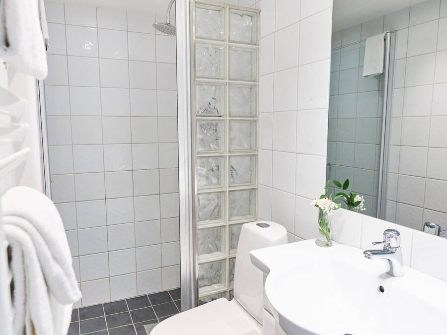 A modern bathroom with a white sink, toilet, and shower.