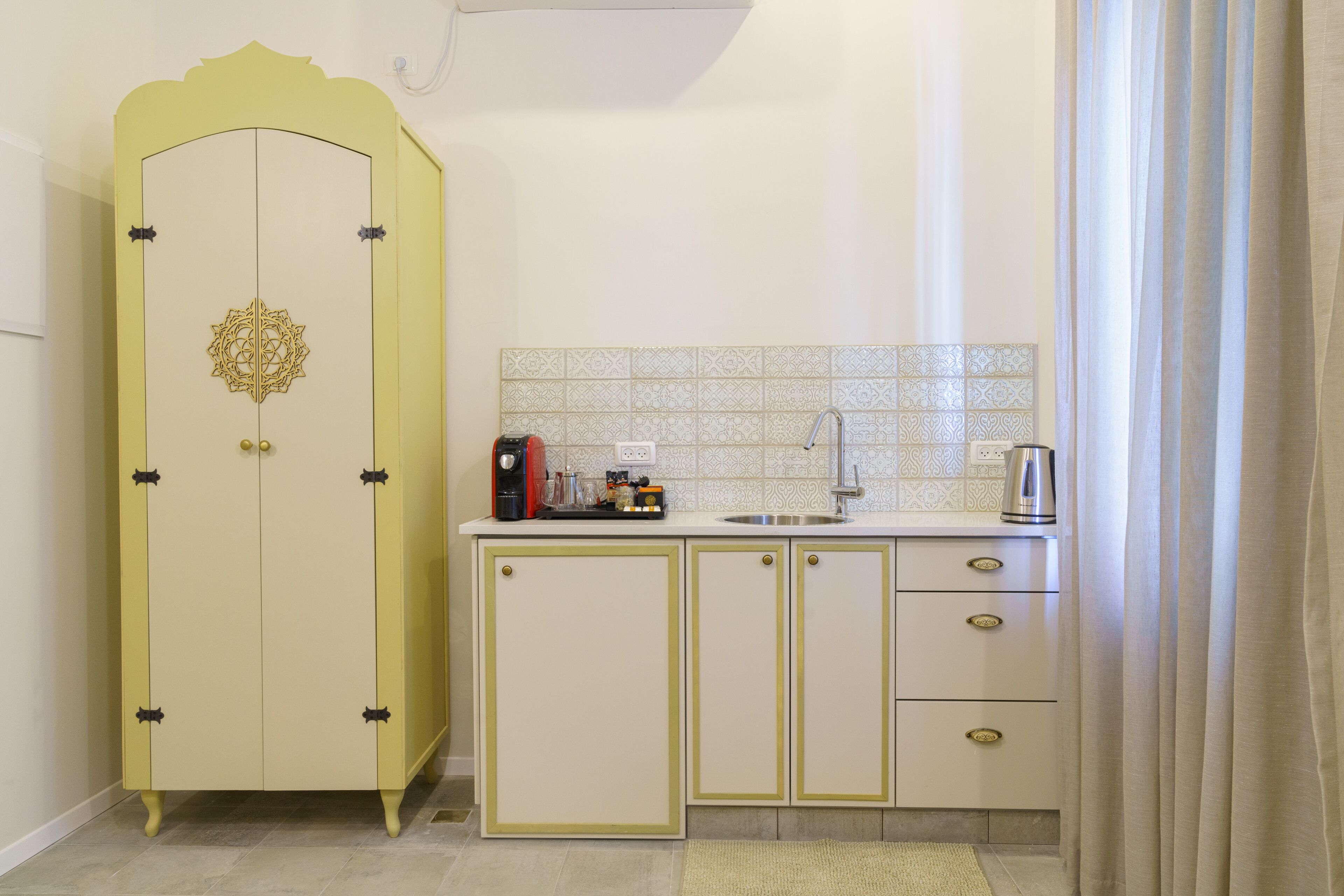 Una cocina compacta con un mueble amarillo, un lavamanos y una cafetera.