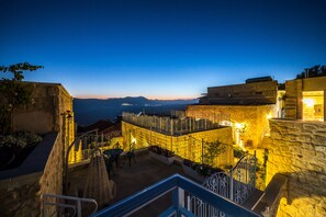 A courtyard with stone walls, a staircase, and a view of distant mountains. - The Way Inn (Safed)