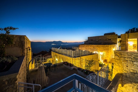 A courtyard with stone walls, a staircase, and a view of distant mountains.