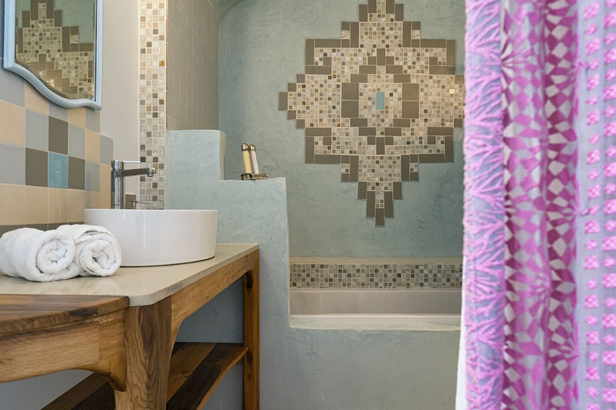 A bathroom with a sink, mirror, and a shower area.
