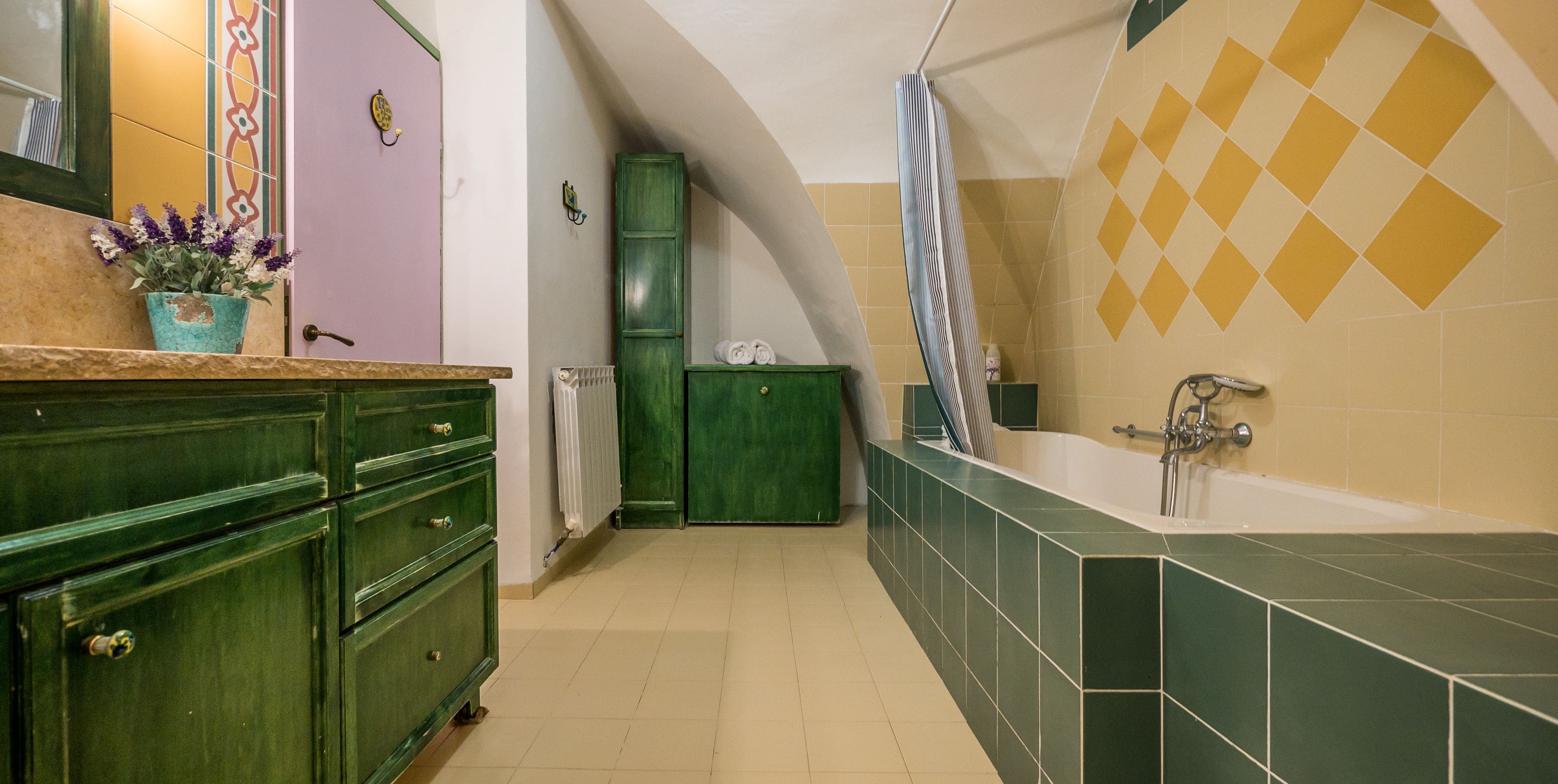 Un baño estrecho con tocador verde, bañera y cortina de ducha.