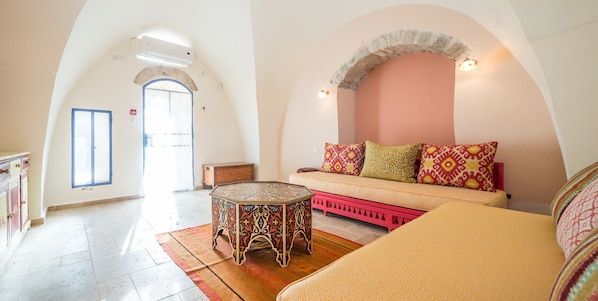 Amplia sala de estar con un sofá, una mesa de centro estampada y vistas a una puerta que da al exterior.