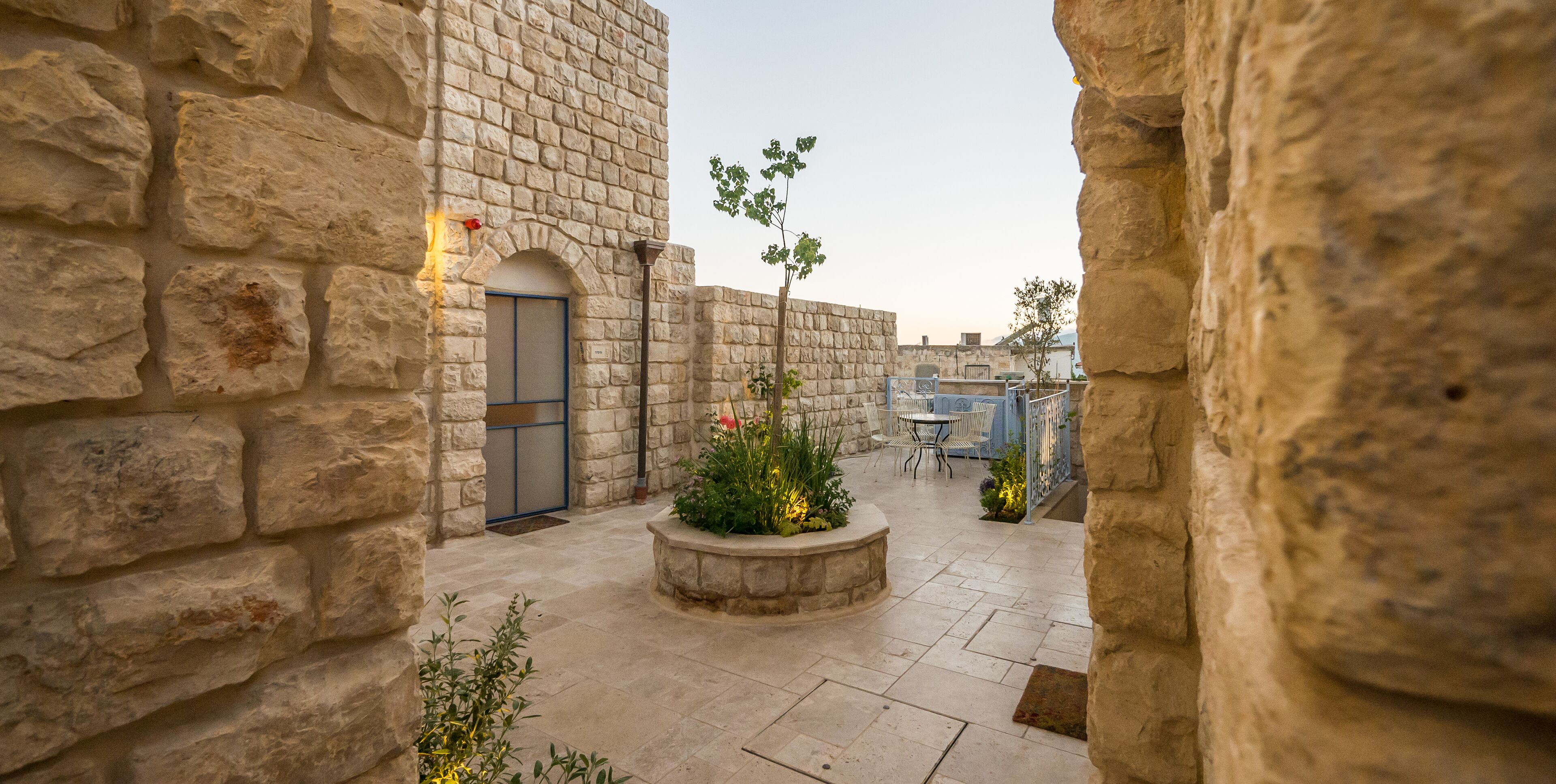 A stone courtyard with a door, a small garden, and outdoor seating.