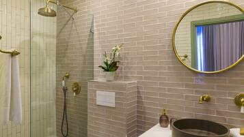 Un baño con ducha, un lavabo de gran tamaño y un espejo con marco dorado.