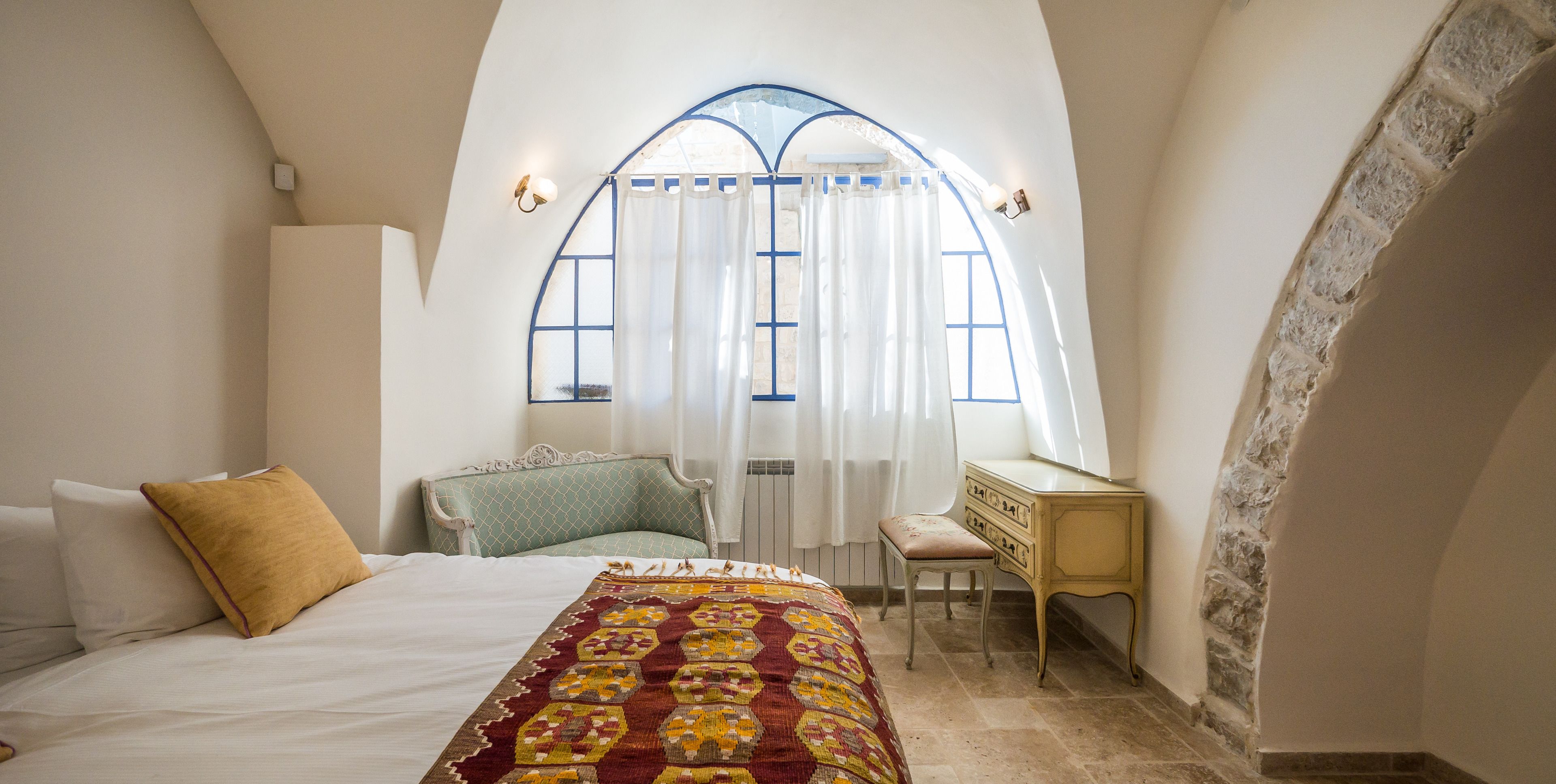 Un dormitorio con una cama, un escritorio y una ventana con cortinas.