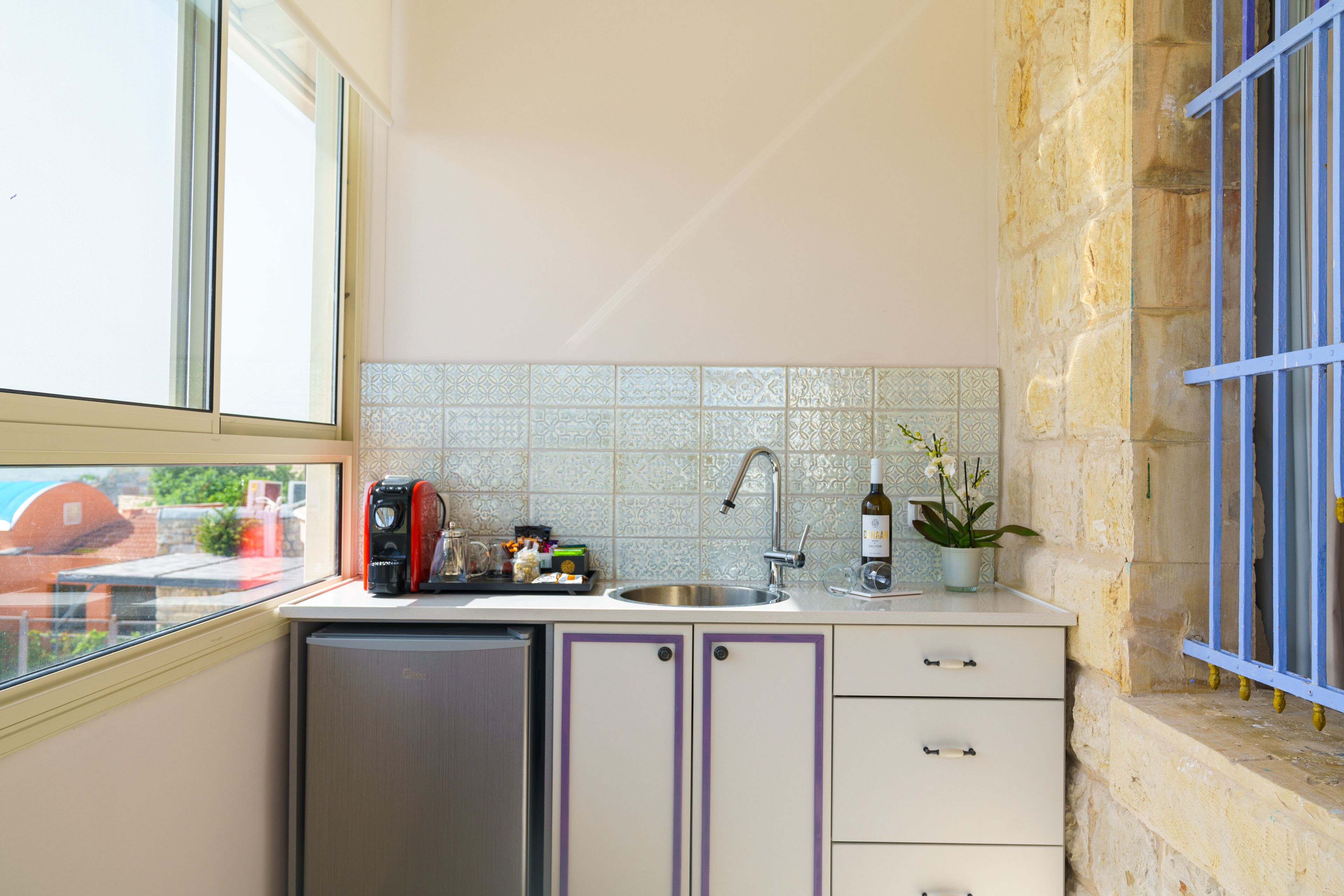 Cocina compacta con lavavajillas integrado, un lavamanos y una ventana.