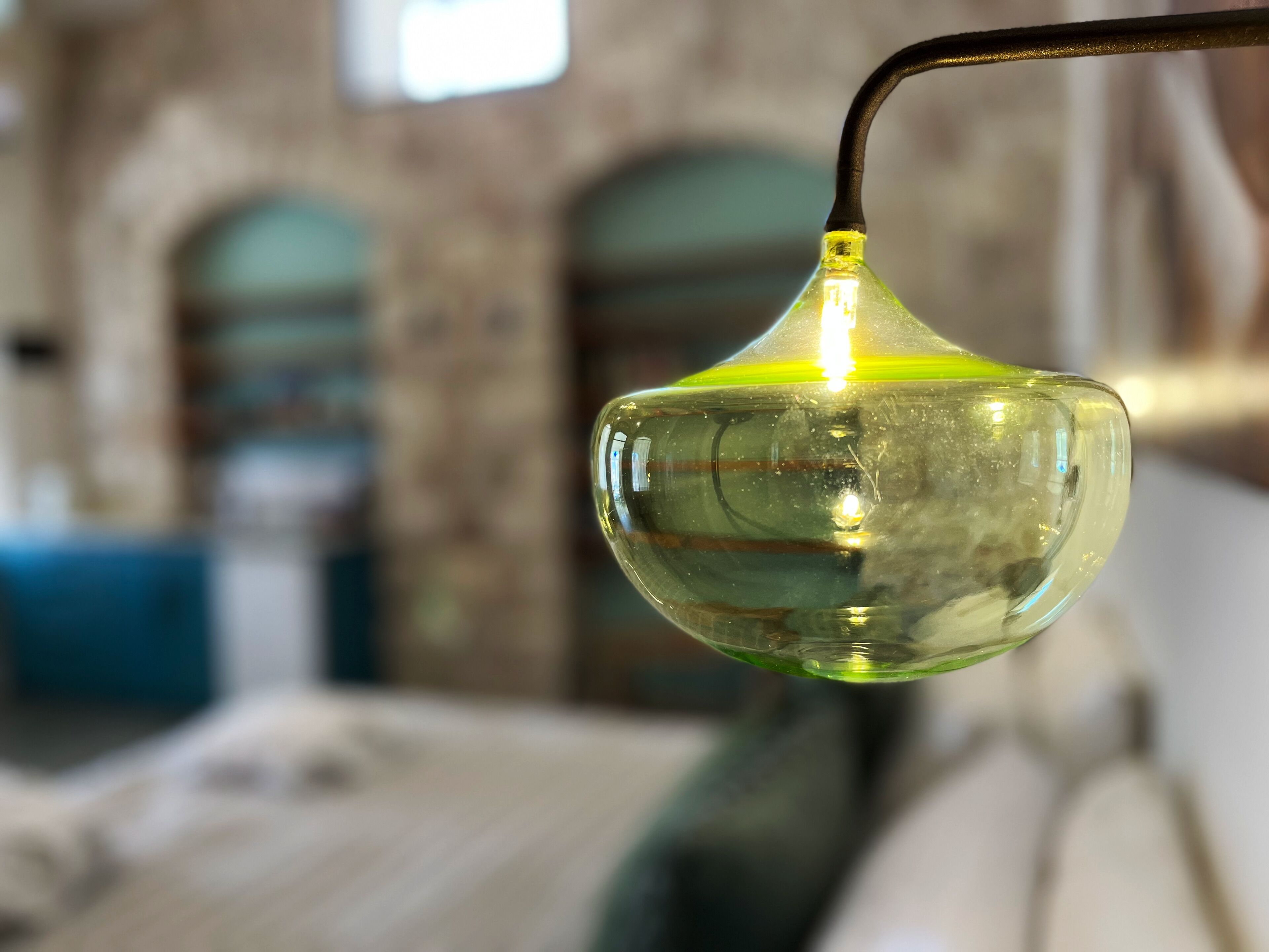 Un objeto de vidrio transparente con luz en su interior, colgado de un gancho metálico.