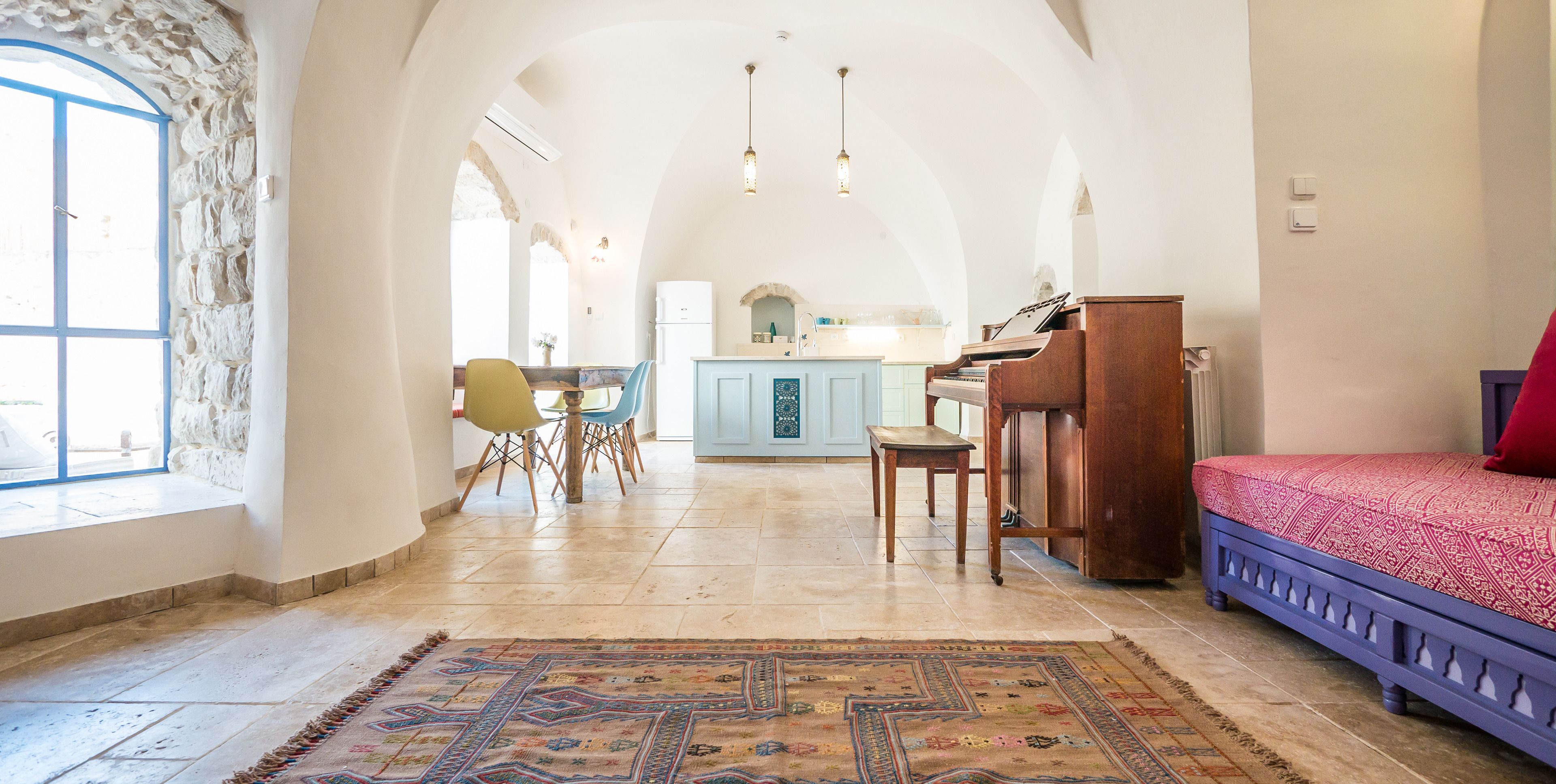 Een ruime kamer met een piano, een eethoek en uitzicht op de keuken.