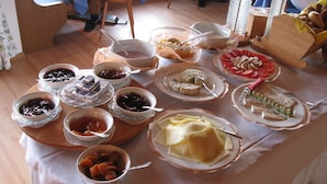 A table with various dishes and bowls of food, including fruits, pastries, and a cake. - Pension Weihergut (Cermes)