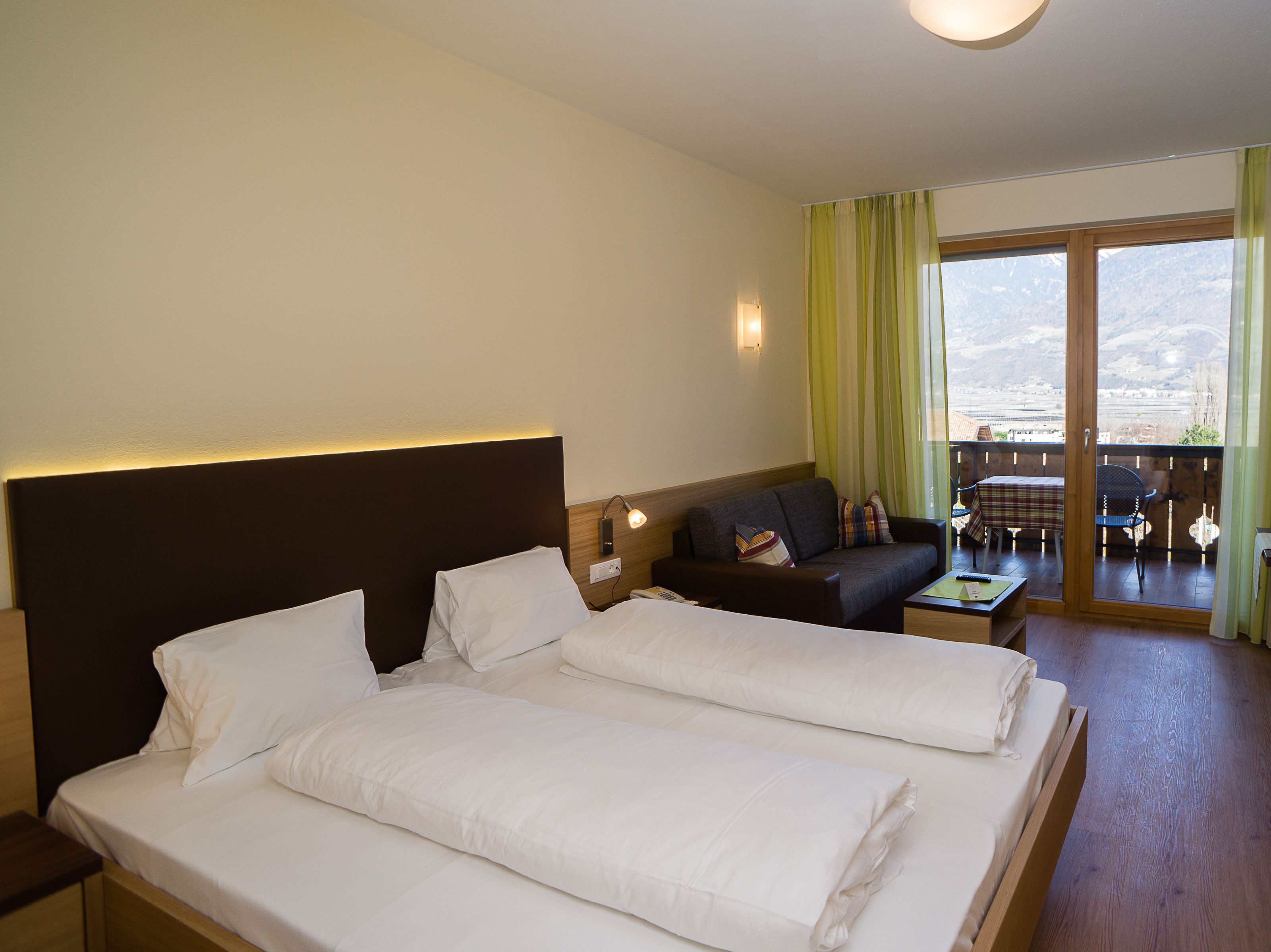 Ein Hotelzimmer mit zwei Betten, einem Sofa, einem Tisch und einem Balkon mit Blick.