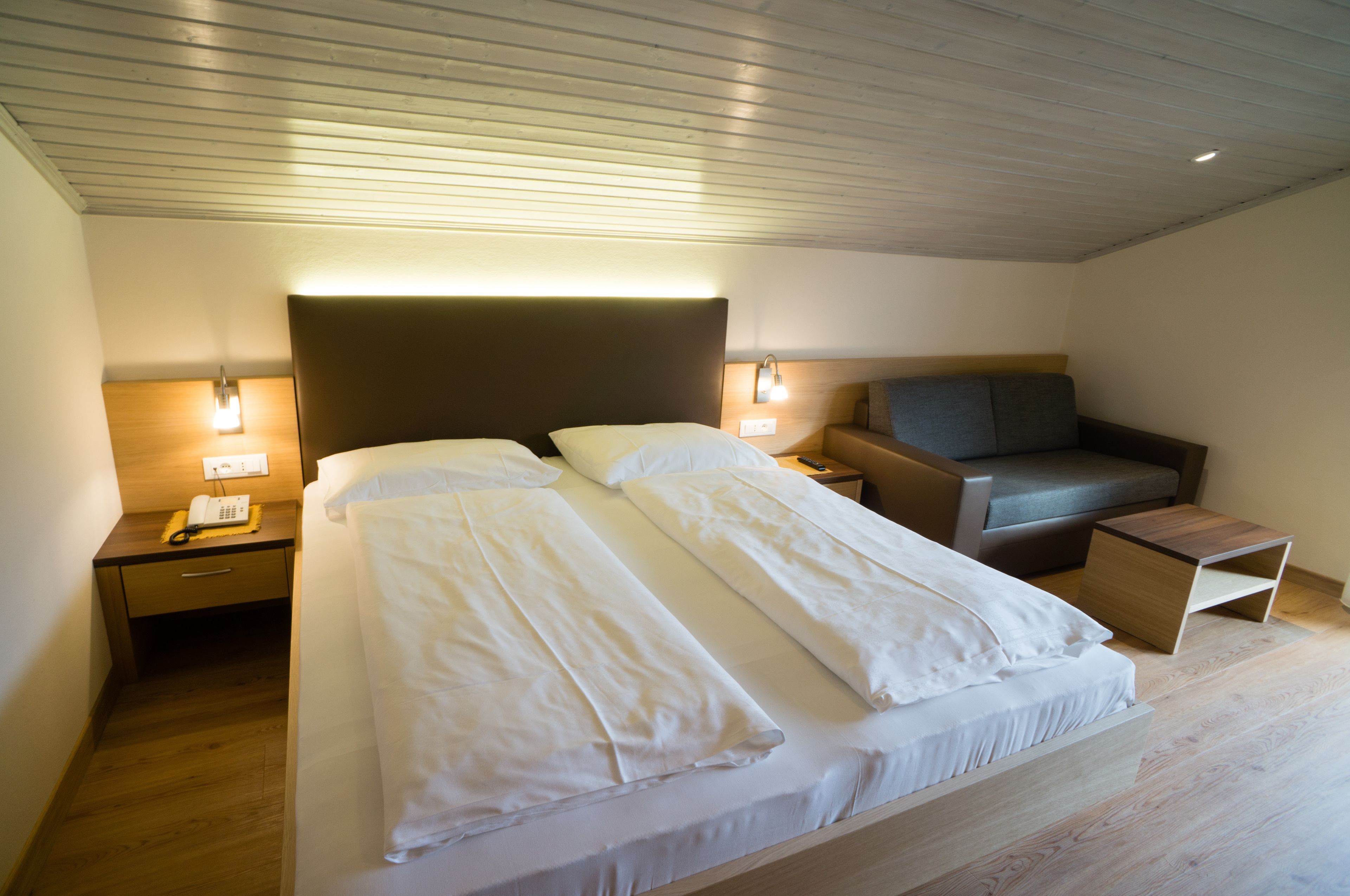 Une chambre d’hôtel moderne avec un grand lit, des tables de chevet, un bureau et un coin salon.