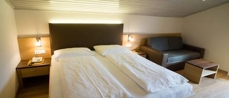 Une chambre d’hôtel moderne avec un grand lit, des tables de chevet, un bureau et un coin salon.