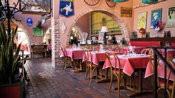 Interior de restaurante con arcos de ladrillo, mesas con manteles rosas y decoración vintage.