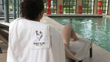Una persona asseguda al costat d'una piscina, amb una tovallola als hombros, i vista cap a l'exterior.