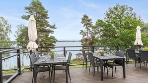 An outdoor deck with tables and chairs, overlooking a body of water and surrounded by trees. - Hotel Ullinge, Sure Hotel Collection by Best Western (Eksjo)