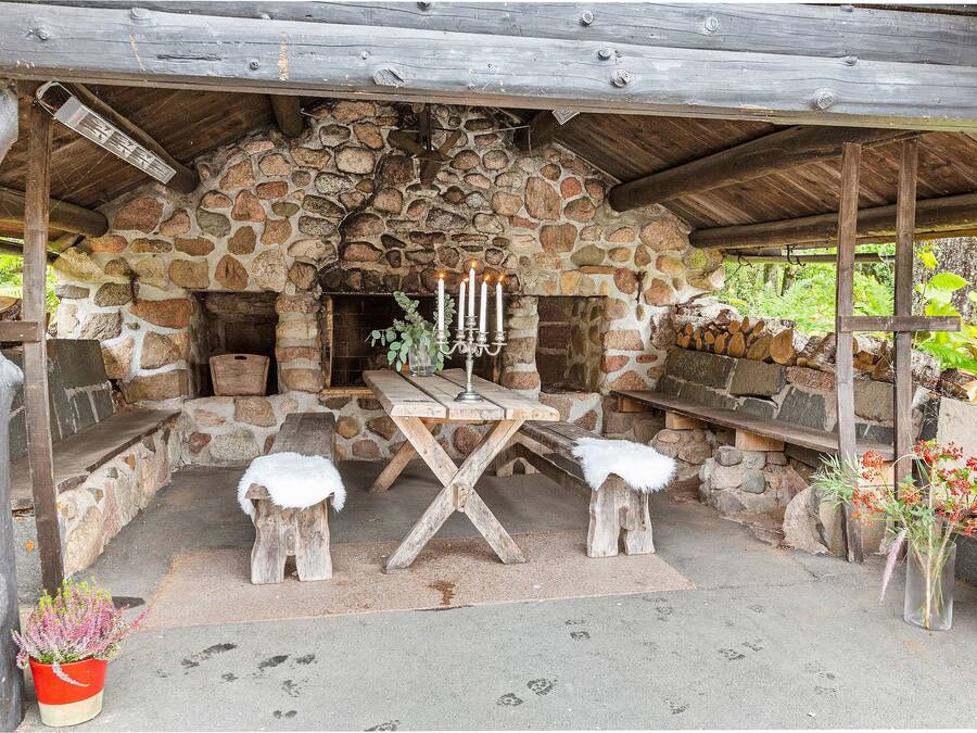 A rustic stone fireplace with a wooden bench and a table with candles.