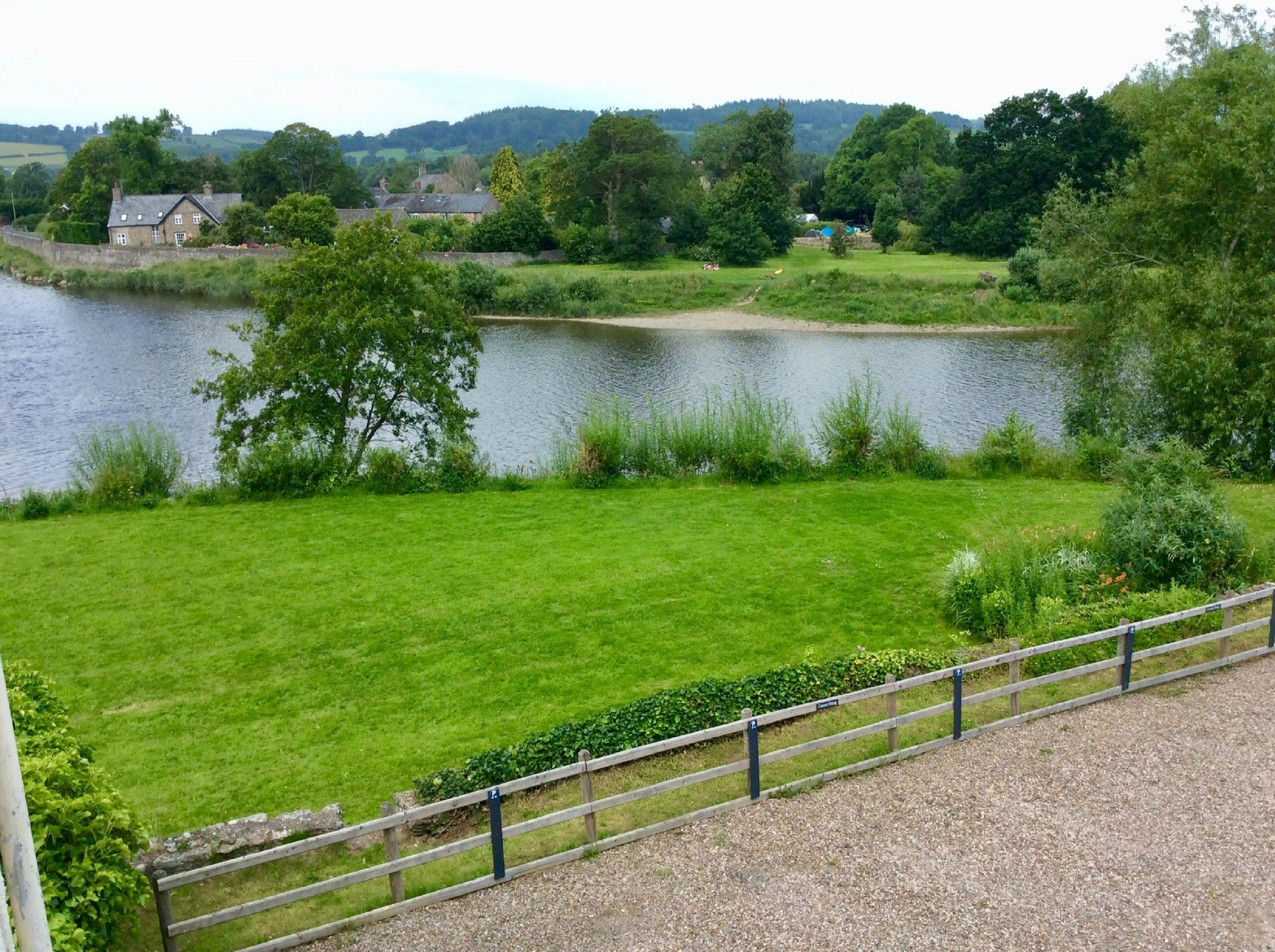 A grassy area with a pond and a wooden fence.