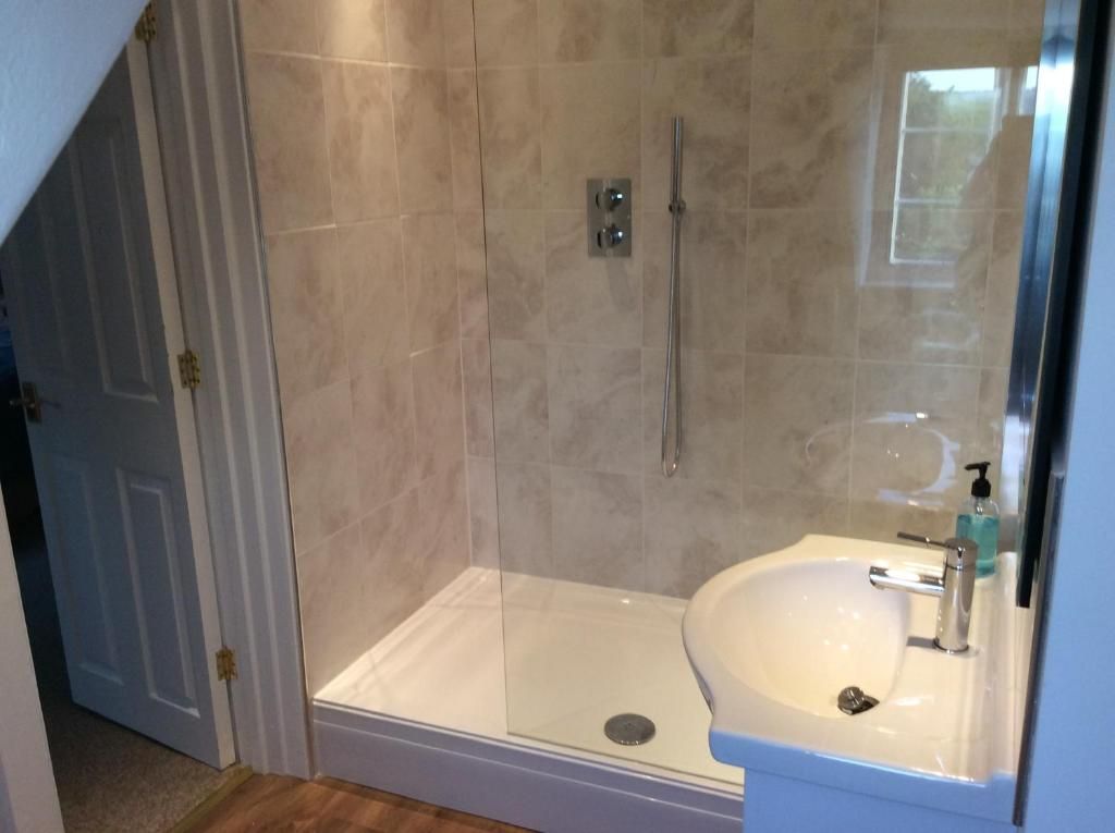 A bathroom with a glass-enclosed shower, a white sink, and a mirror.
