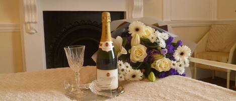 Een tafel met een fles champagne, een glas en een bloemenboeket.