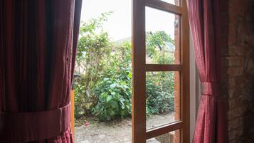 Una ventana con vista a un jardín y un muro de ladrillo.