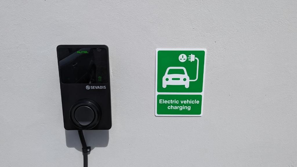 An electric vehicle charging station with a sign indicating its purpose.