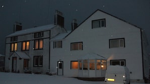 A two-story house with a snow-covered driveway and a parked van in front. - The Mansion Bed & Breakfast (Whitehaven)