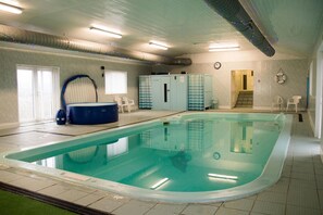 Una piscina interior con un jacuzzi, una escalera y una puerta que da a un nivel superior.