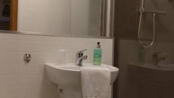 Un baño con inodoro, lavamanos y zona de ducha.