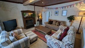 A cozy living room with a fireplace, a sofa set, a coffee table, and a television. - The Mansion Bed & Breakfast (Whitehaven)