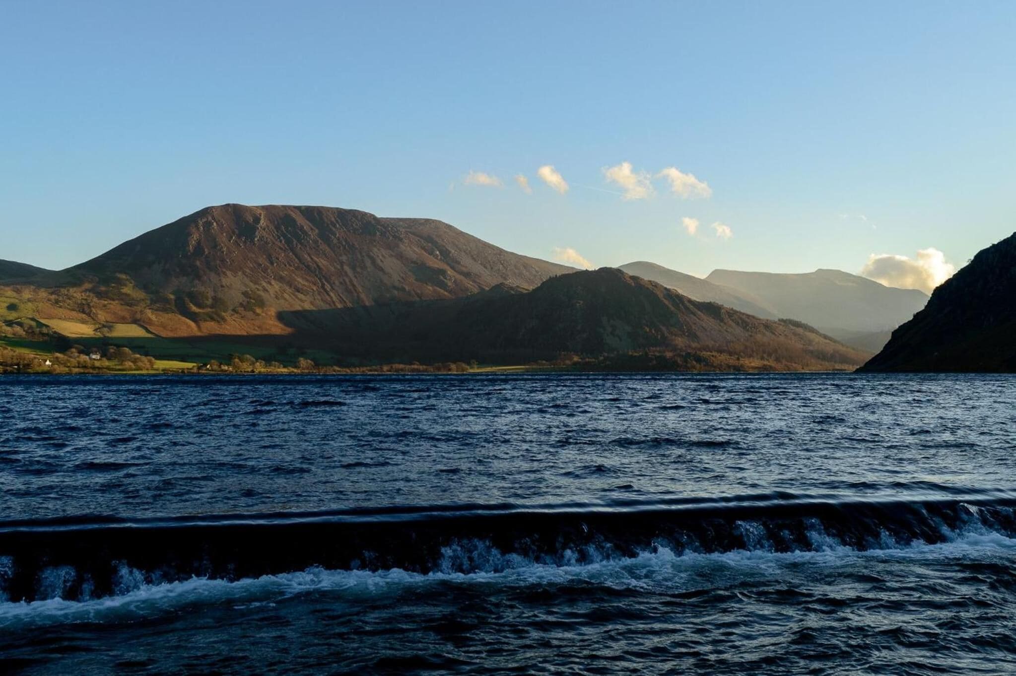 A lake with mountains in the background and waves in the foreground.